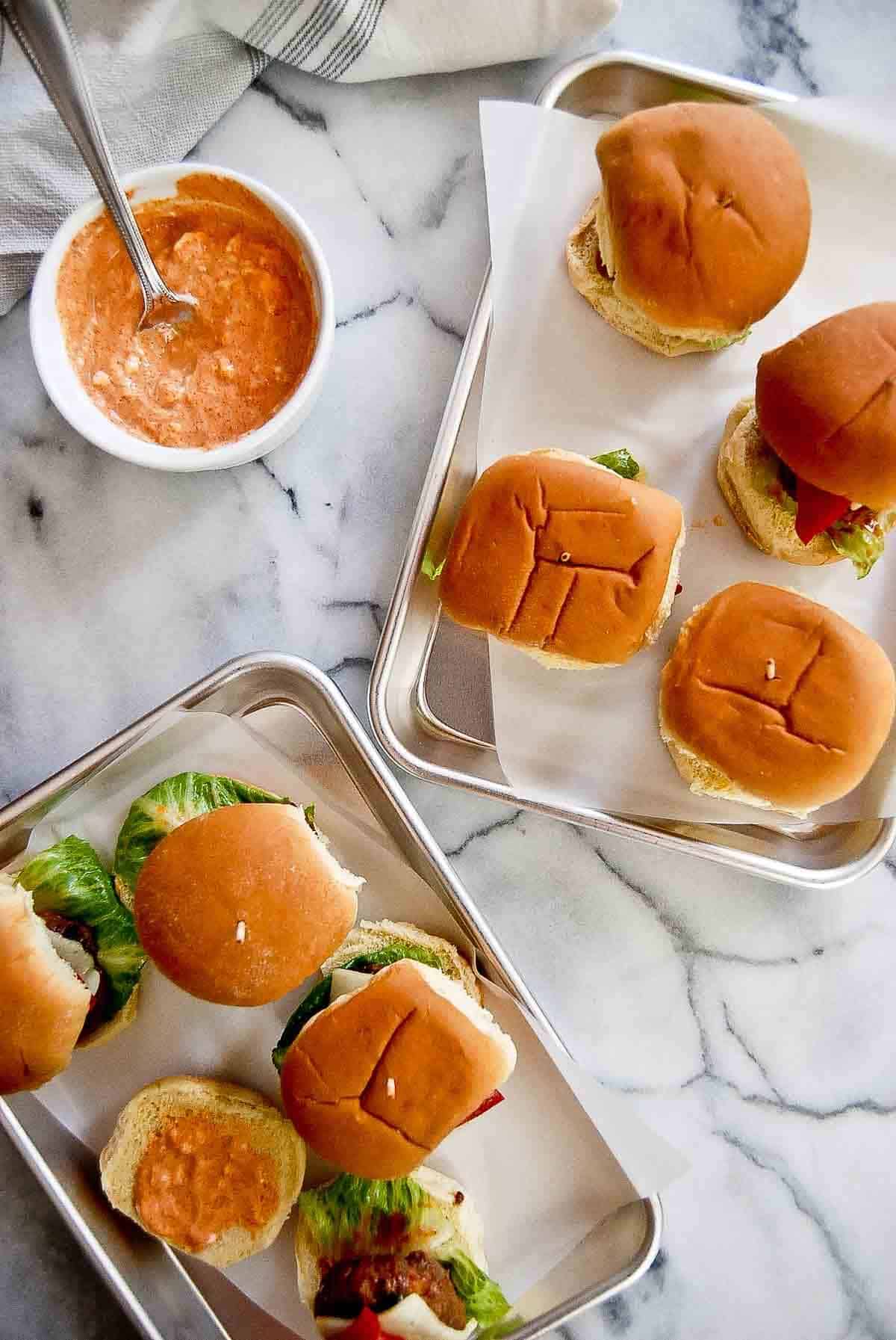 spanish sliders on tray with bowl of red pepper mayo to the side.