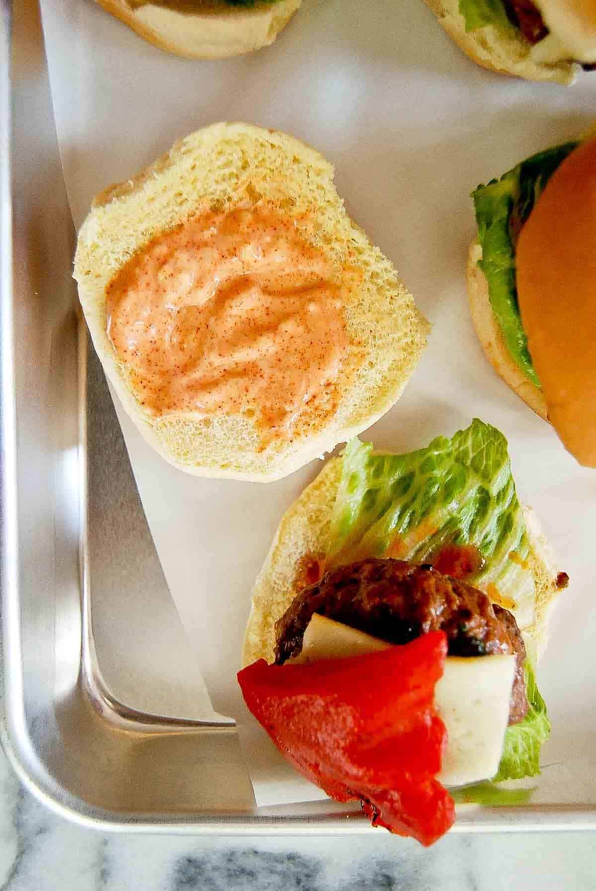 spanish slider on bun with top bun open and red pepper mayo spread across it.