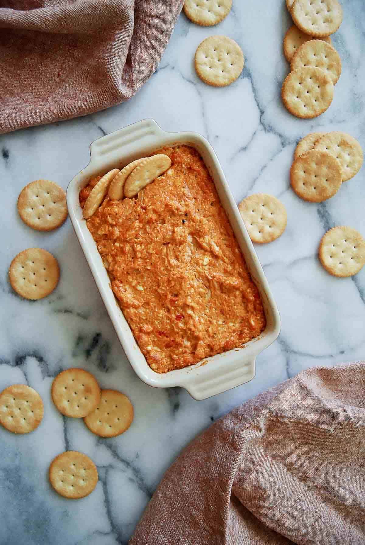 hot cajun crab dip in baking dish with ritz crackers.