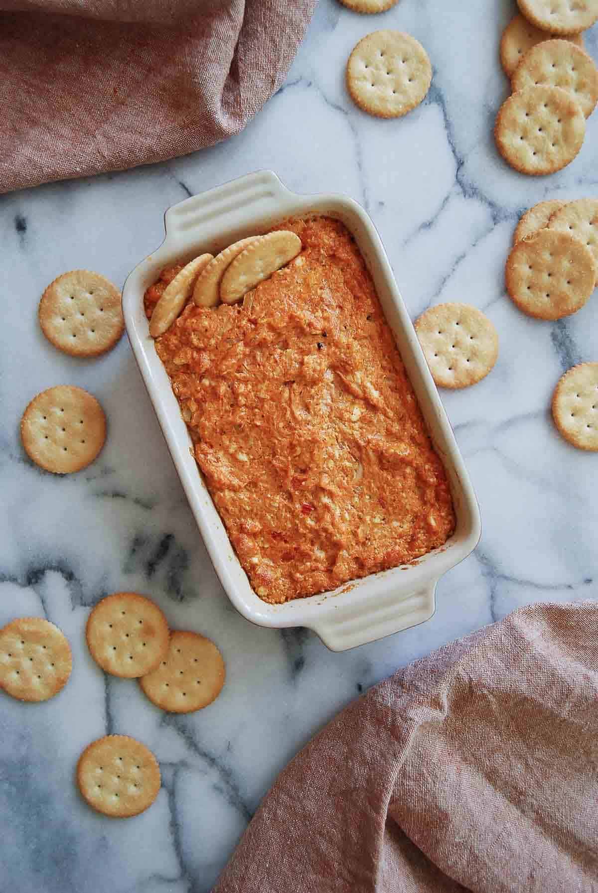 hot cajun crab dip in baking dish with ritz crackers.