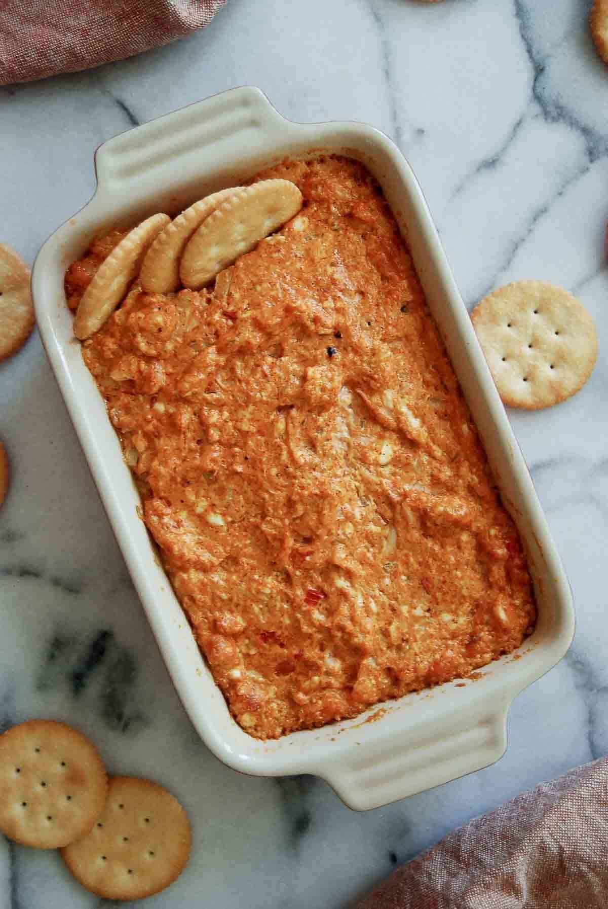 hot cajun crab dip in baking dish with ritz crackers.