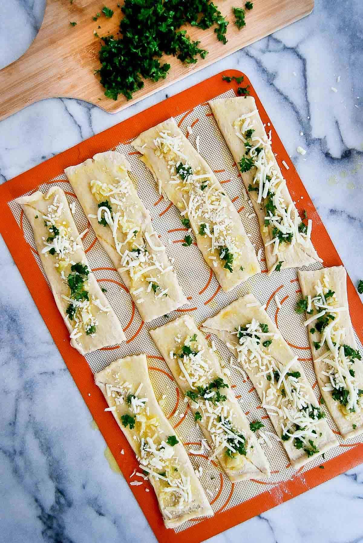 strips of crescent roll dough with cheese, garlic butter and herb mixture on top.