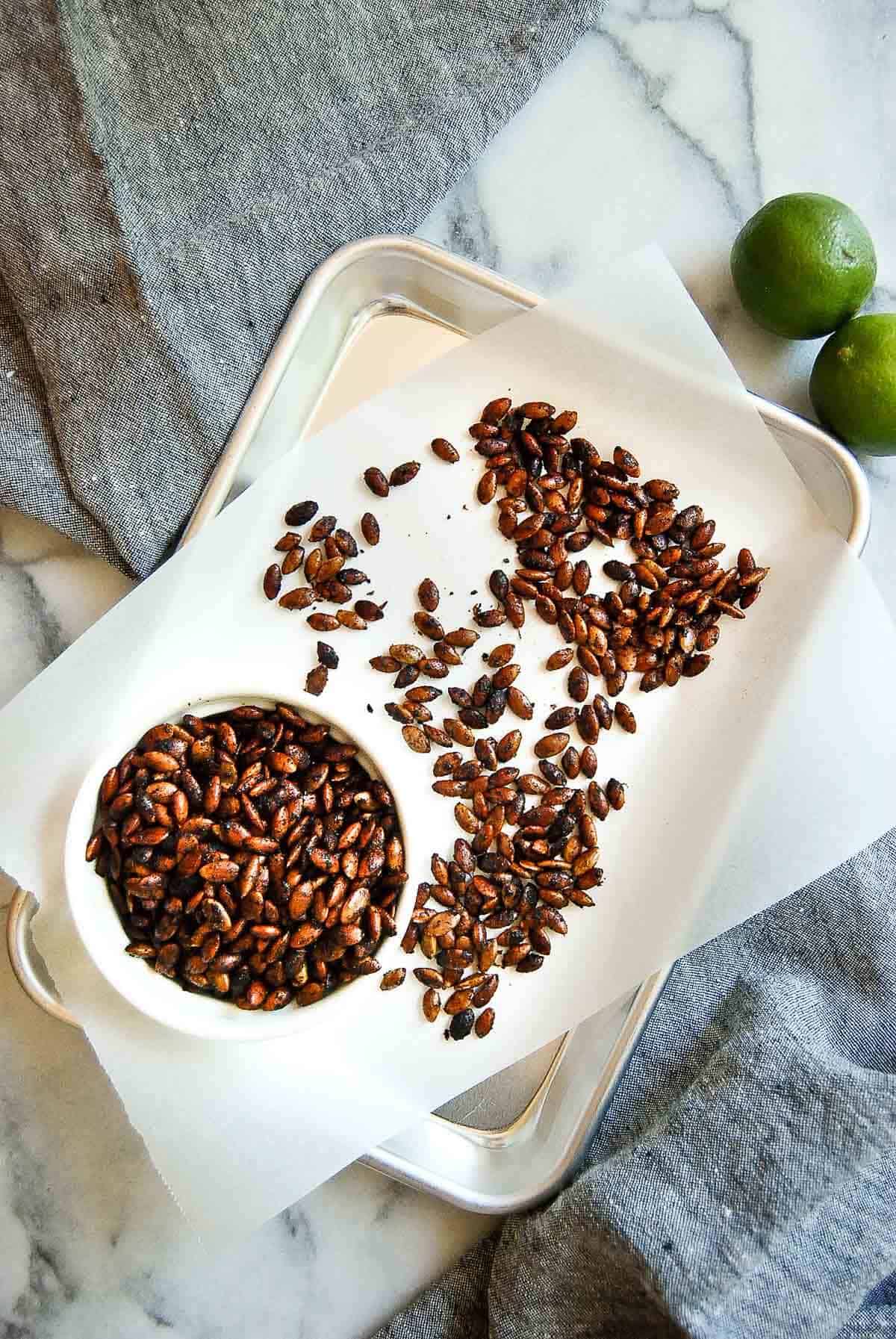 Roasted chili lime pepitas in bowl and on serving sheet.