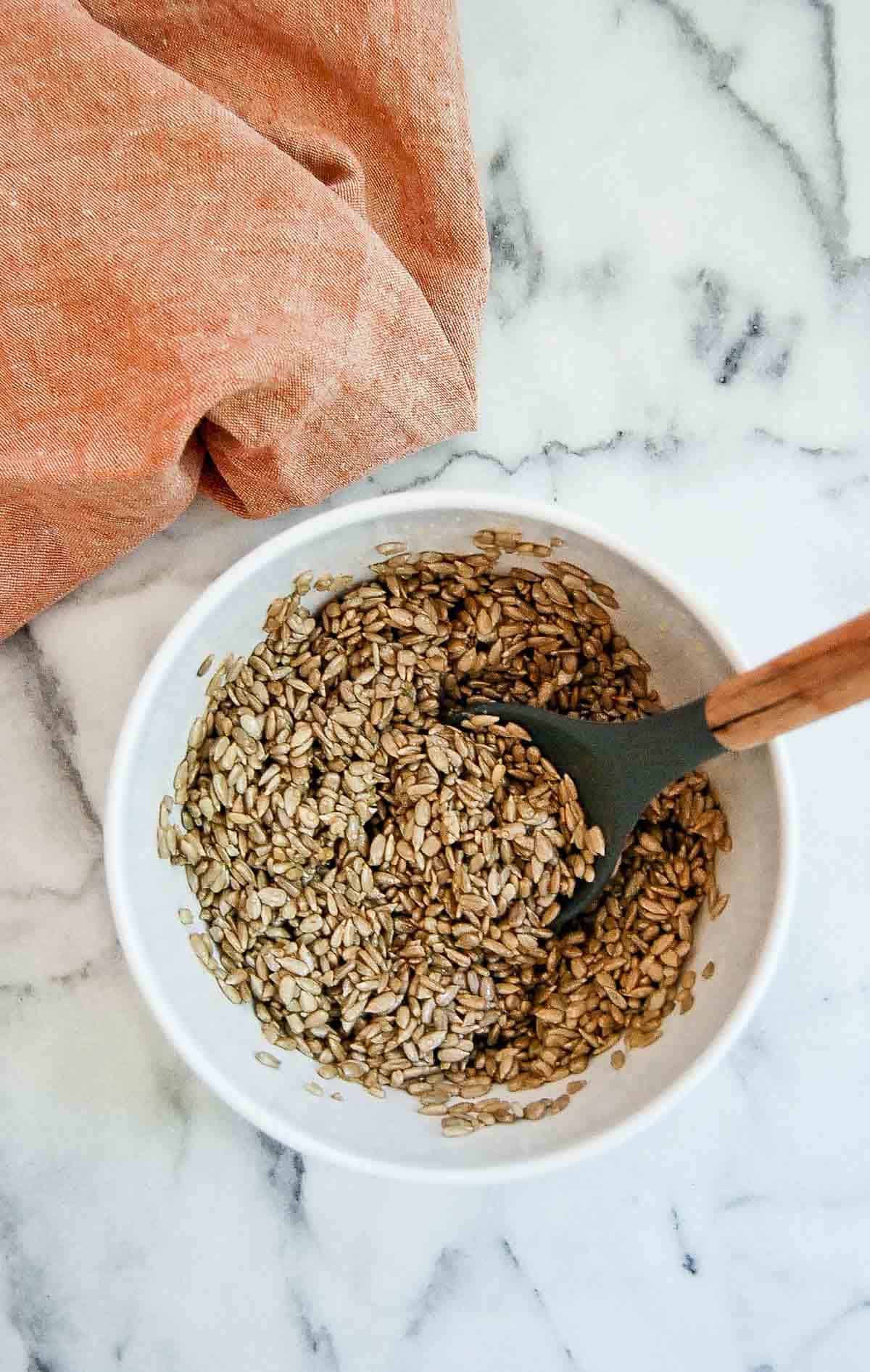 sunflower seeds in mixing bowl with honey seasoning.