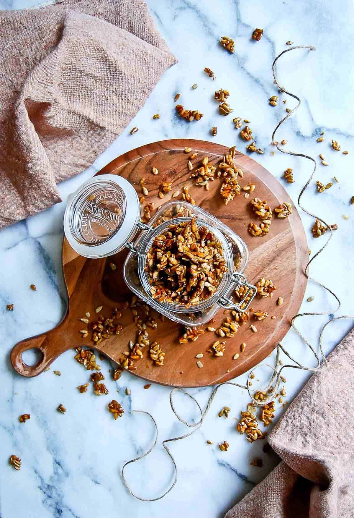 honey roasted sunflower seeds in jam jar on cutting board.