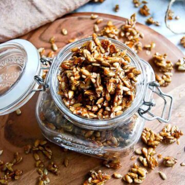 closeup of honey roasted sunflower seeds in jam jar on cutting board.