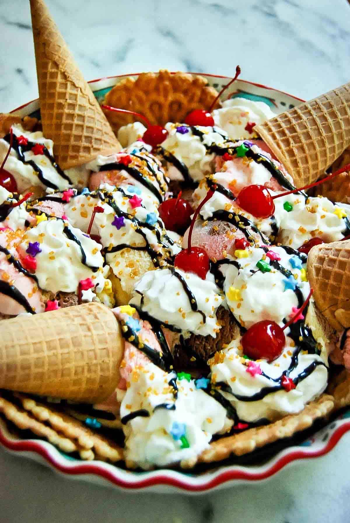side view of ice cream nachos with whipped cream, cherries and sugar cones.