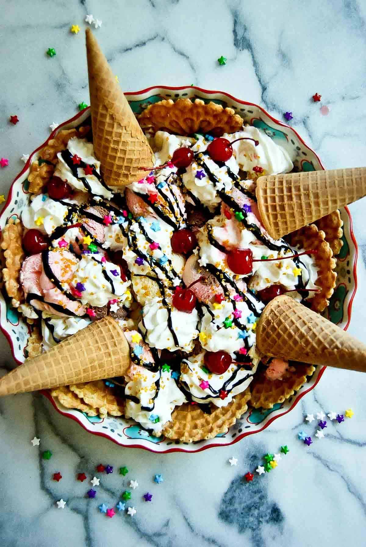 ice cream nachos with whipped cream, sprinkles and cherries on countertop.