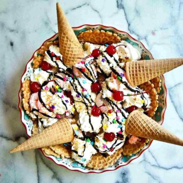 ice cream nachos with whipped cream, chocolate syrup, sprinkles and cherries.