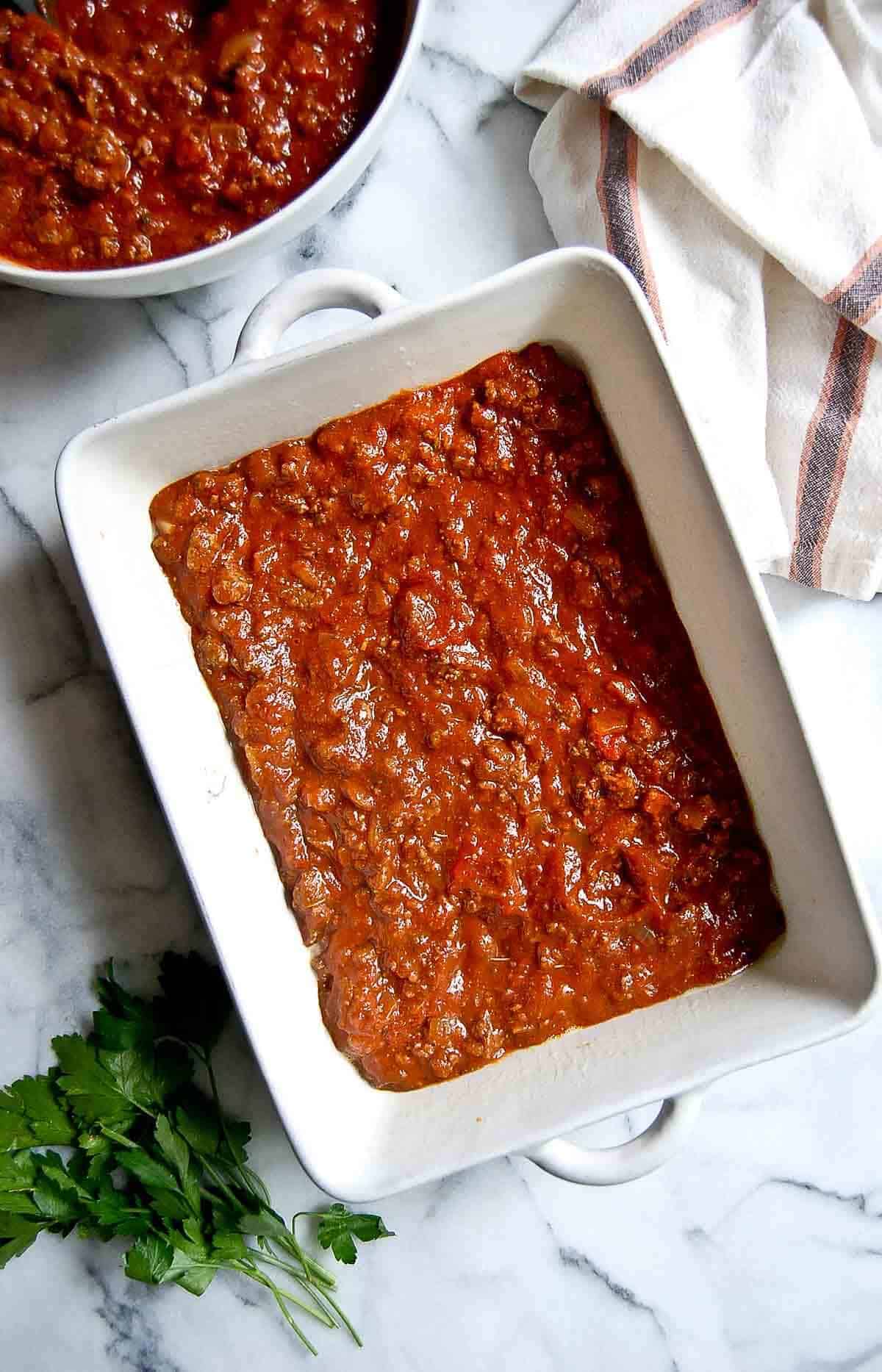 casserole dish with pasta sauce at the bottom of the dish.