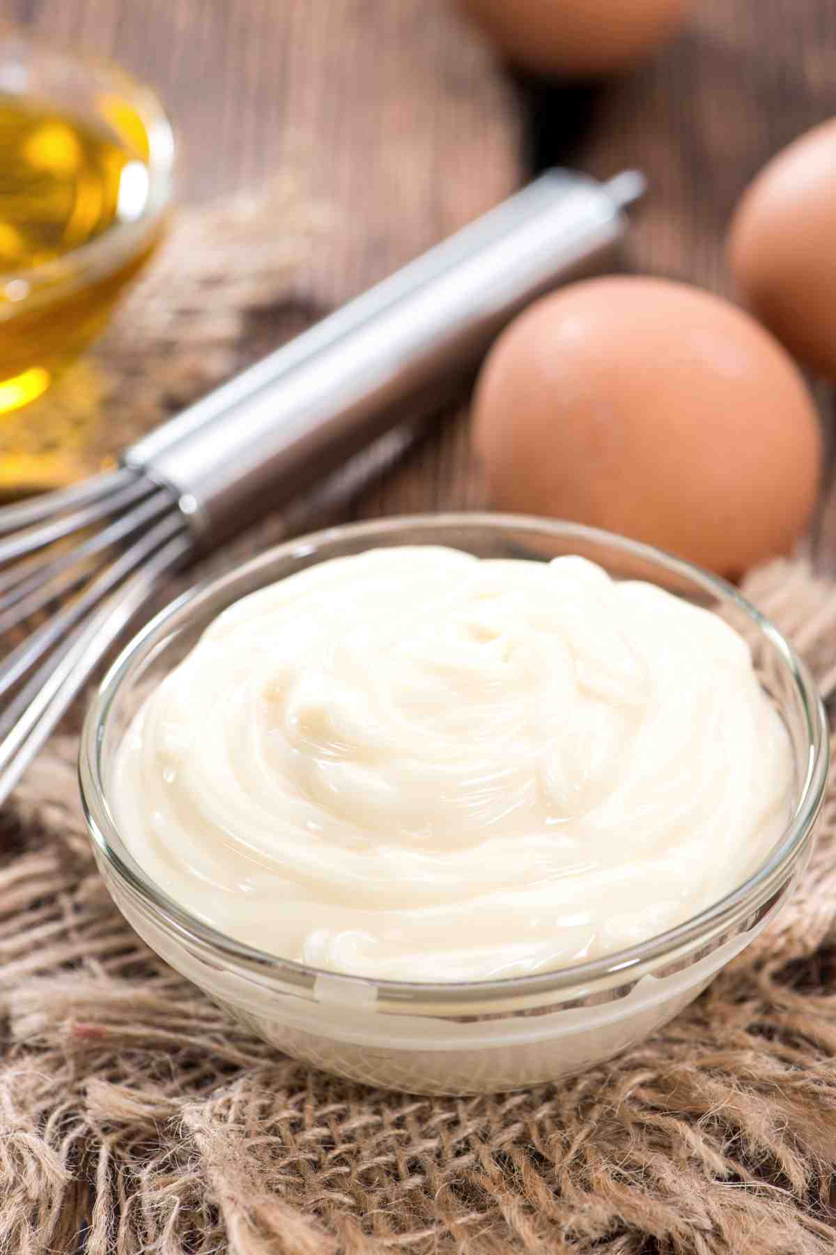 mayonnaise in a bowl with eggs in the background.