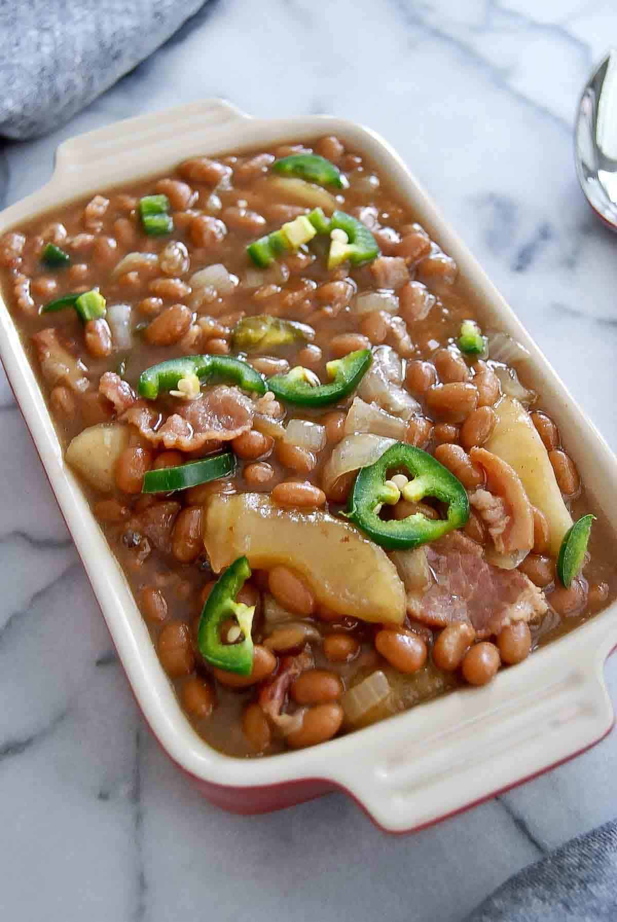 side view of slow cooker apple pie baked beans in dish on countertop.