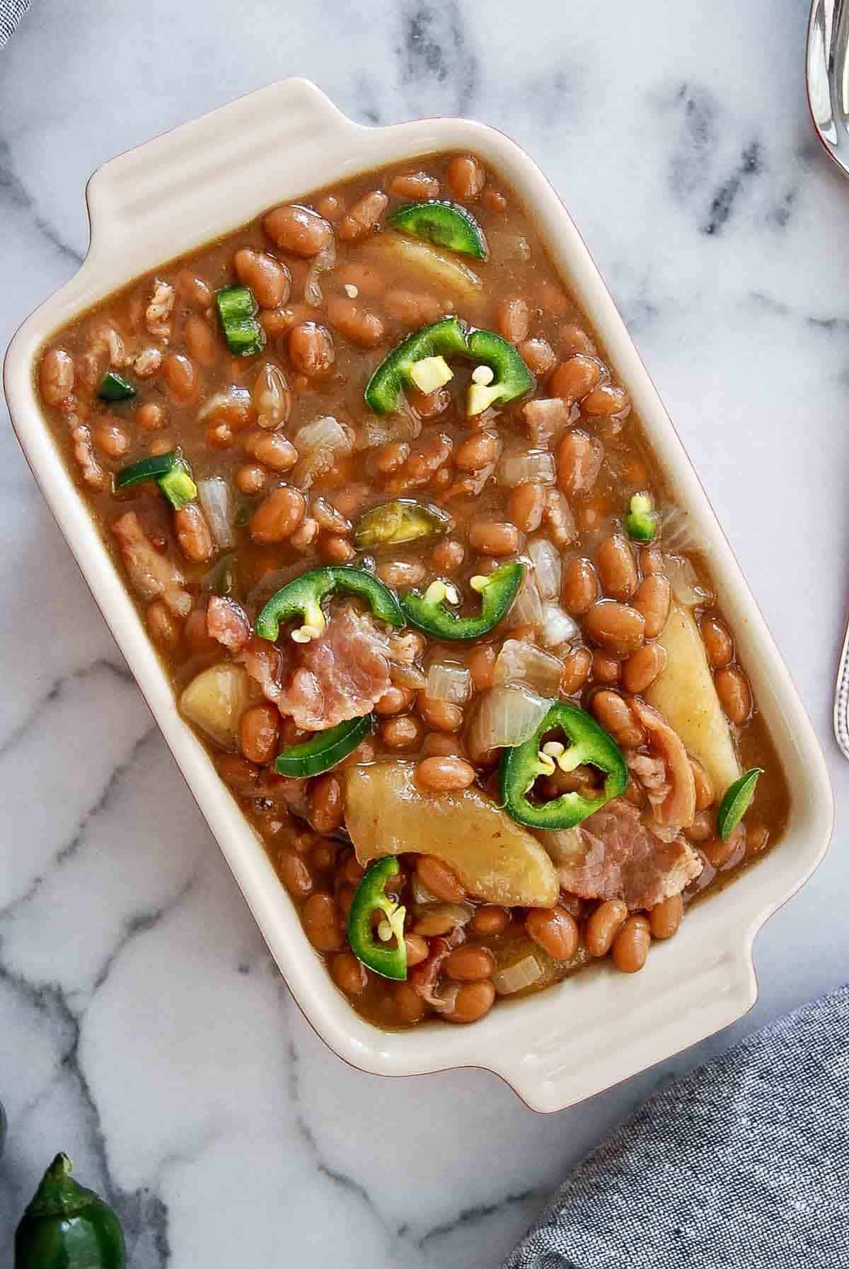 slow cooker apple pie baked beans in serving dish on countertop.