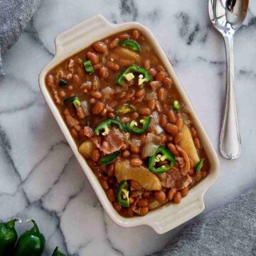 close up of apple pie baked beans with bacon and jalapeno in dish on counter.