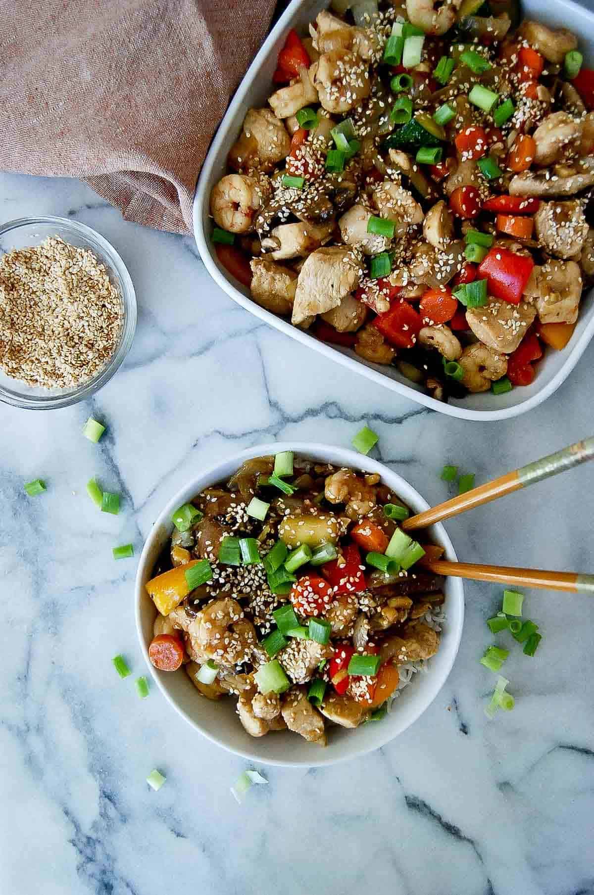 chicken and shrimp stir fry with garlic ginger sauce in bowl on counter.