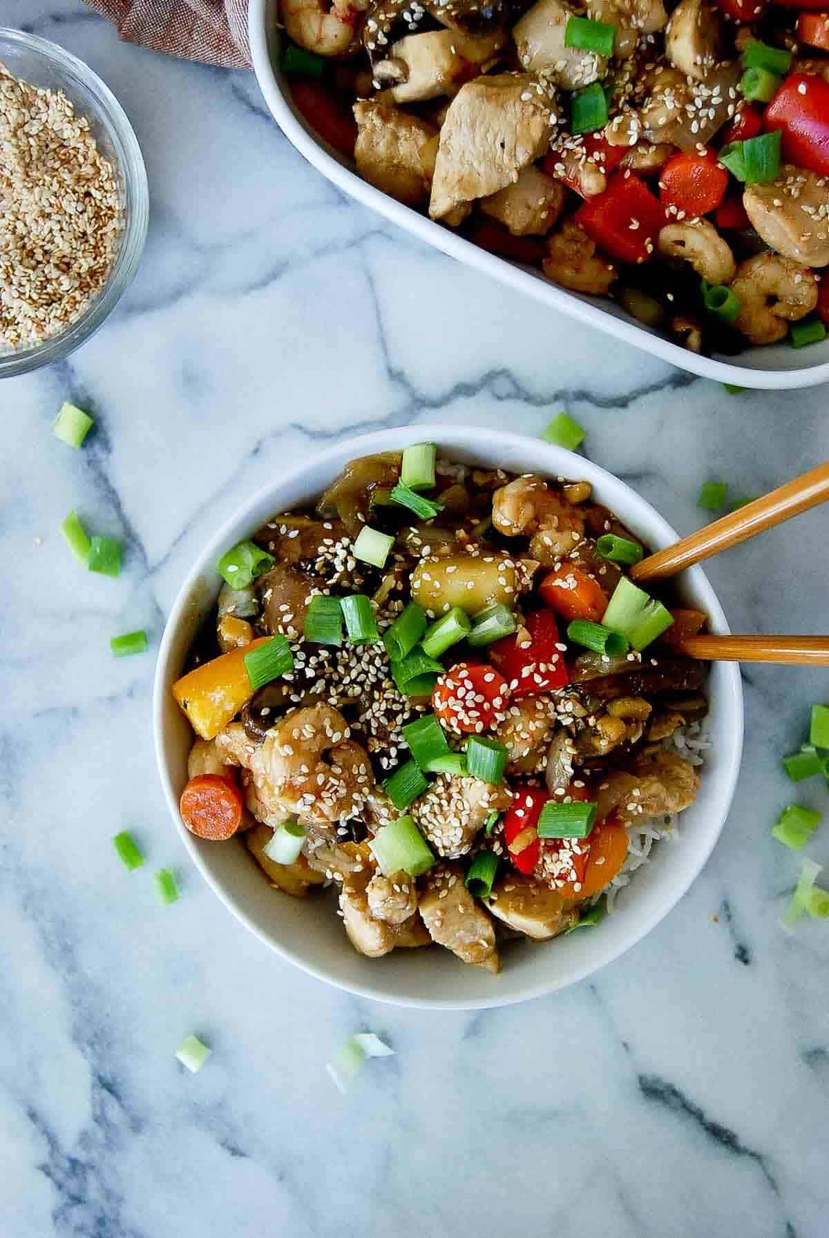 closeup of chicken and shrimp stir fry with chopsticks in bowl.