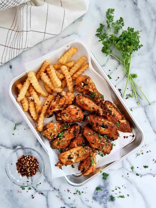 baked spanish chicken wings with garlic on tray with french fries.