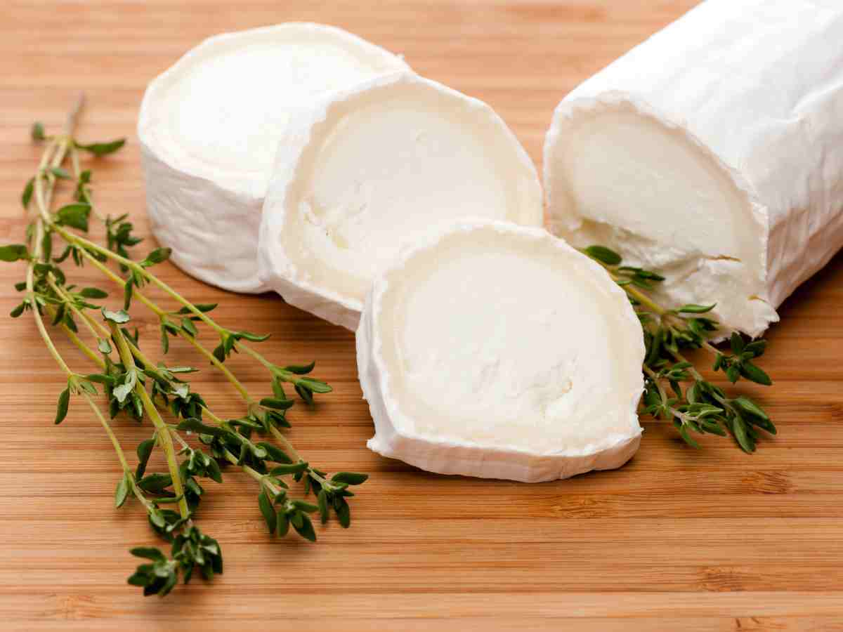 log of goat cheese, sliced on cutting board.