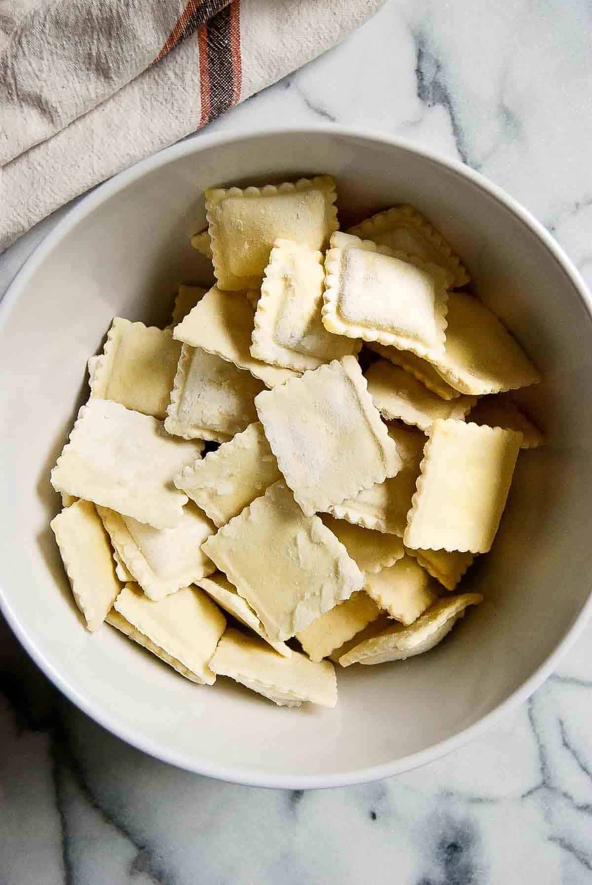 bowl of frozen cheese ravioli on countertop.