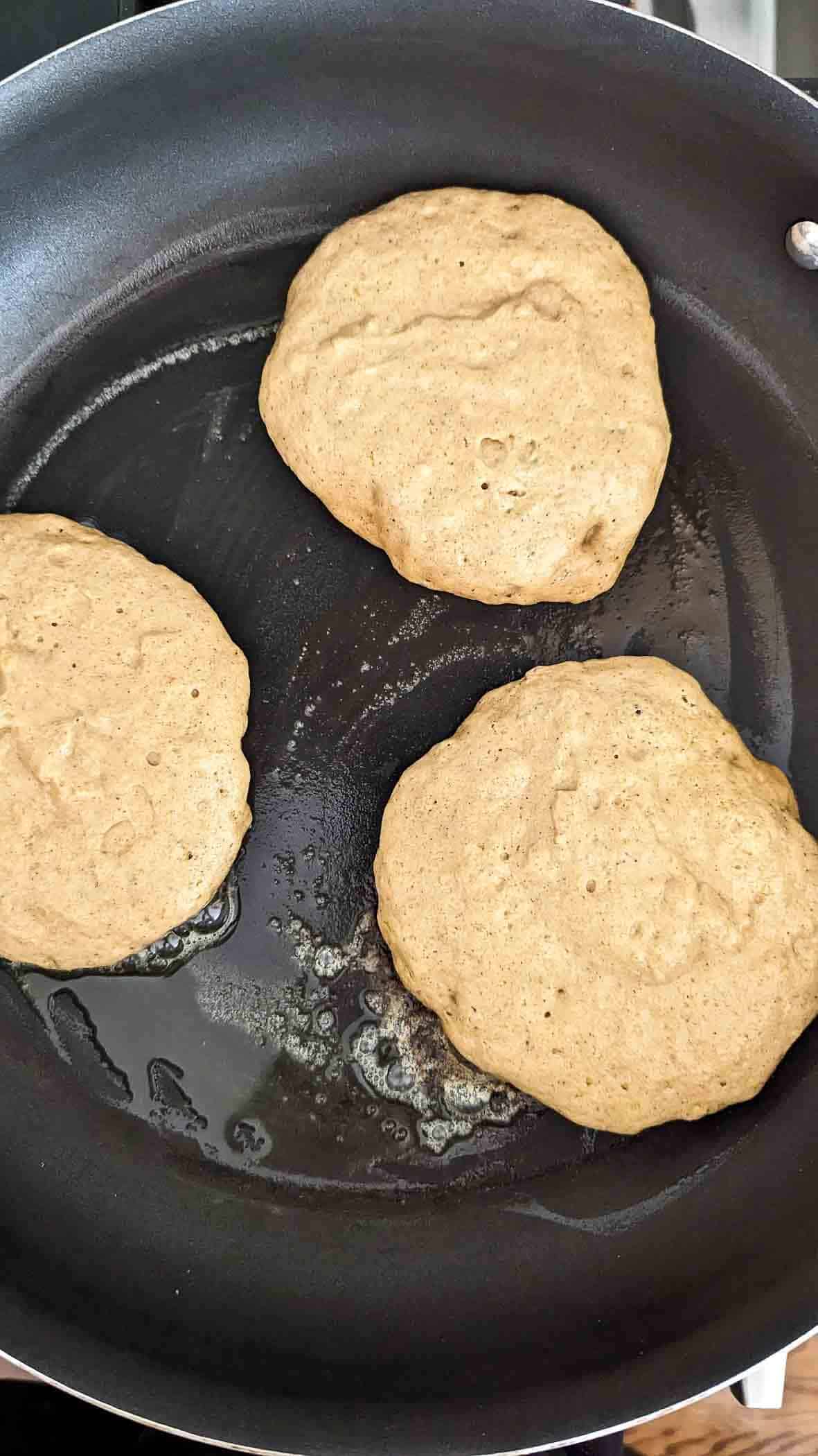 pumpkin pancakes cooking in skillet.