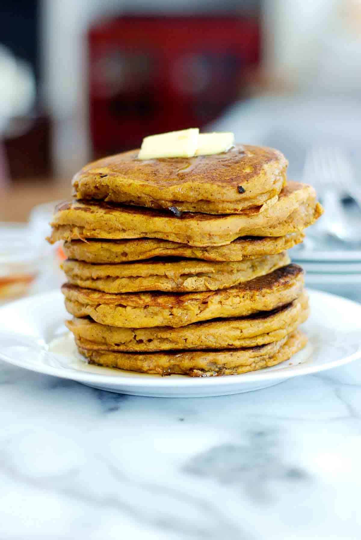 side view of pumpkin pancakes made with pancake mix, stacked, with butter on top.