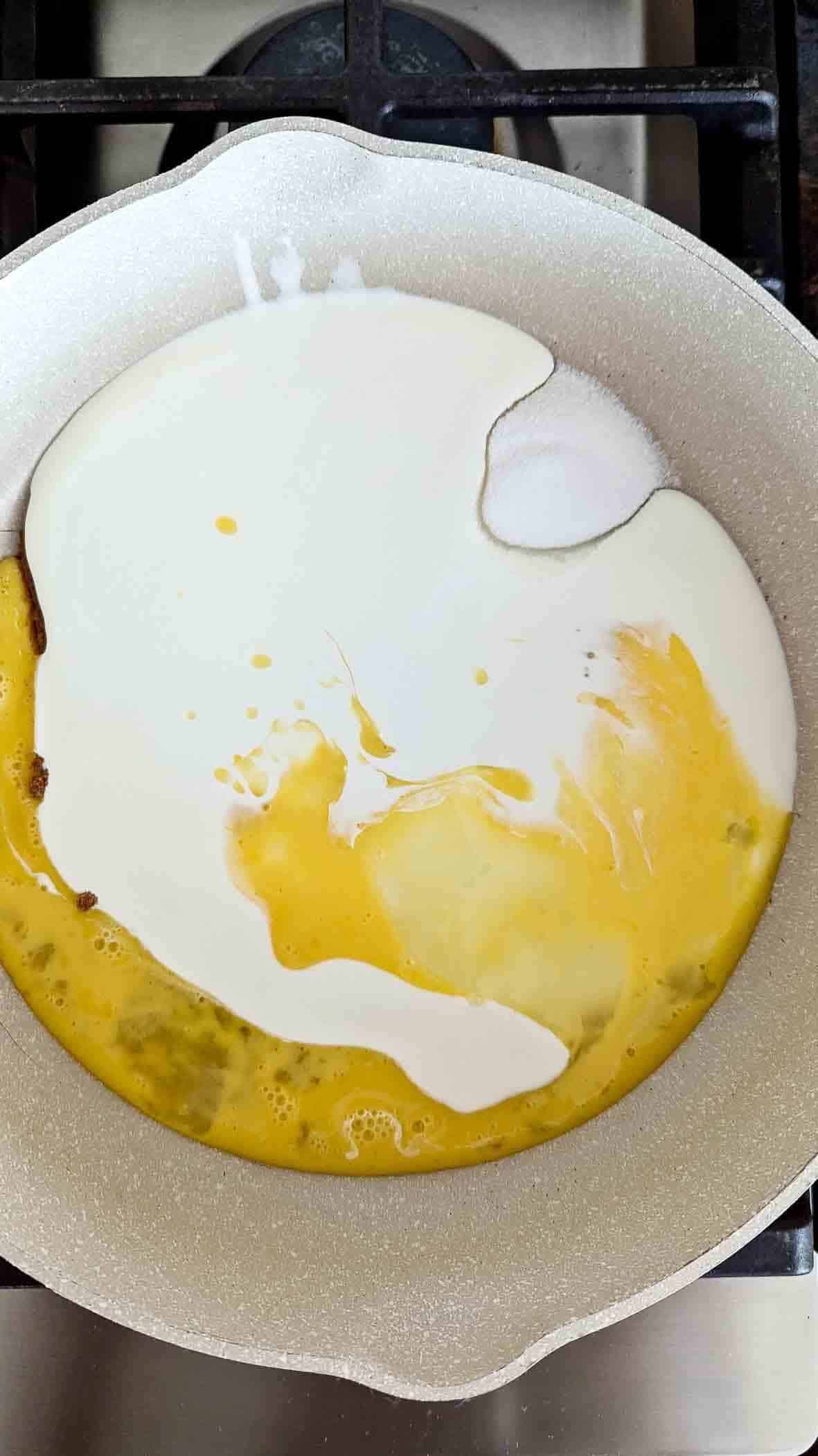 spices and sugar mixed with heavy cream and eggs in saucepan.