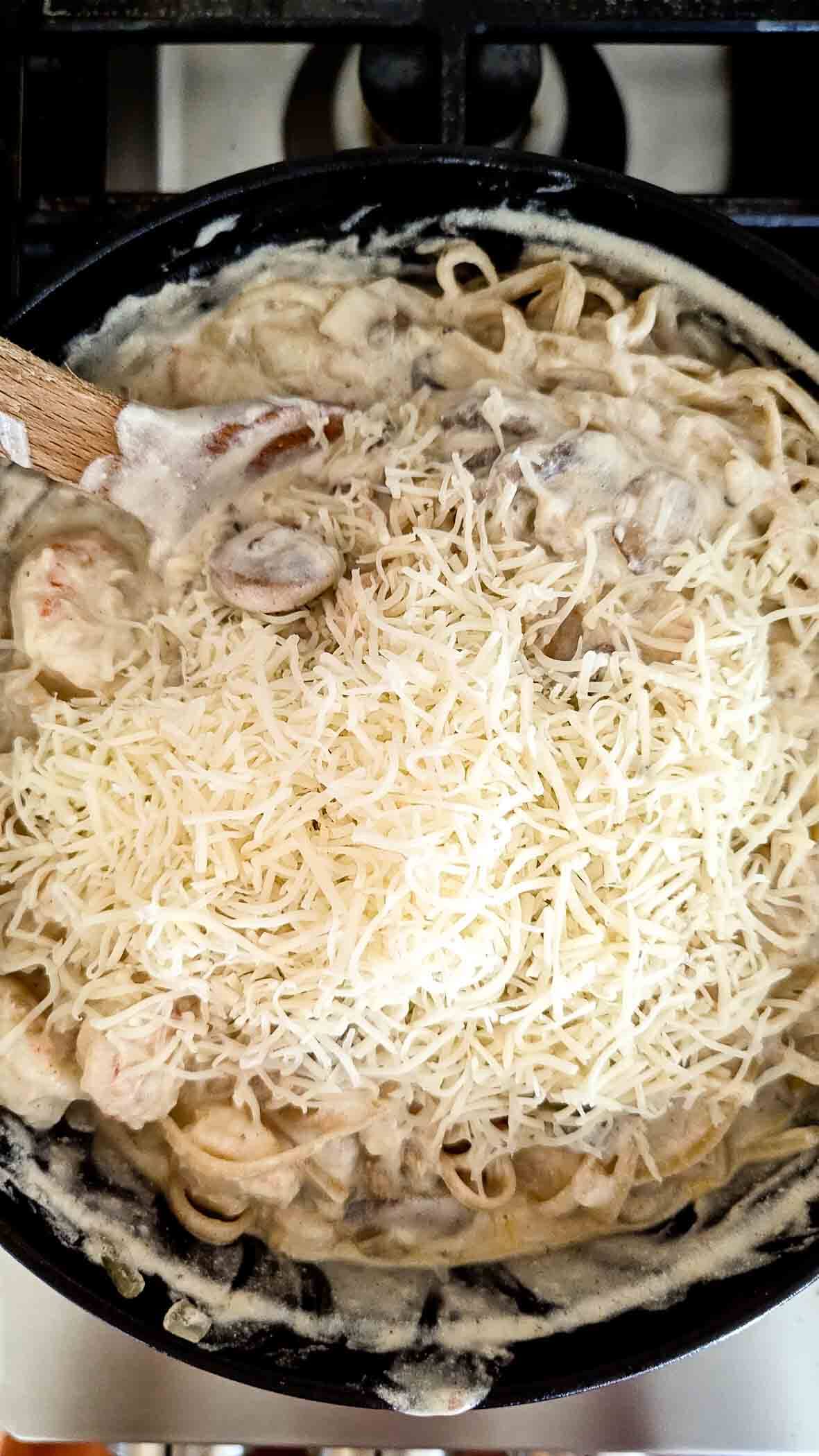 shrimp pasta on stovetop with Parmesan cheese mixed in.