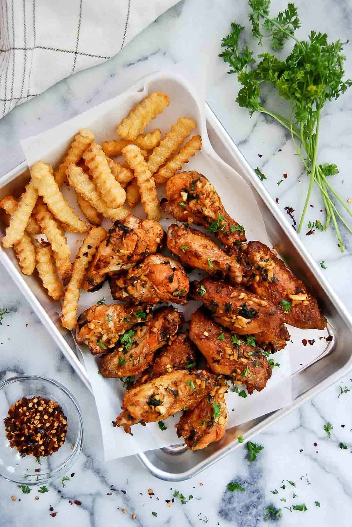 spanish chicken wings with garlic on tray with french fries.