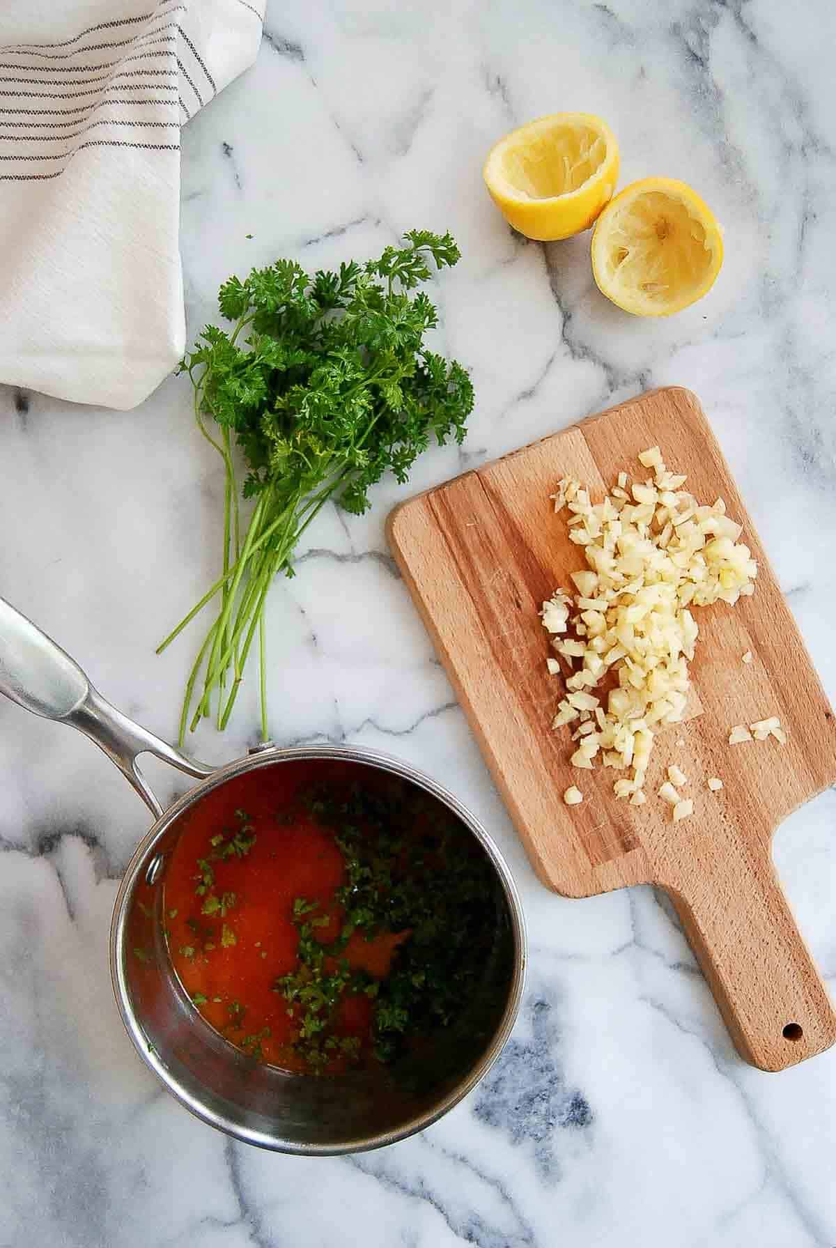 garlic brandy sauce for spanish chicken wings in saucepan, with chopped garlic on the side.