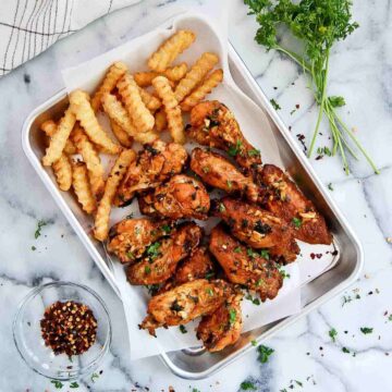 spanish chicken wings with fries on tray.