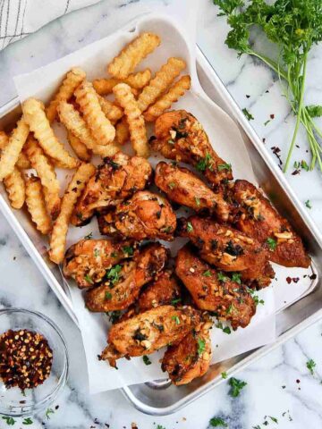 spanish chicken wings with fries on tray.