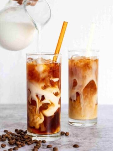 cold brew coffee in cups with cream being poured in.