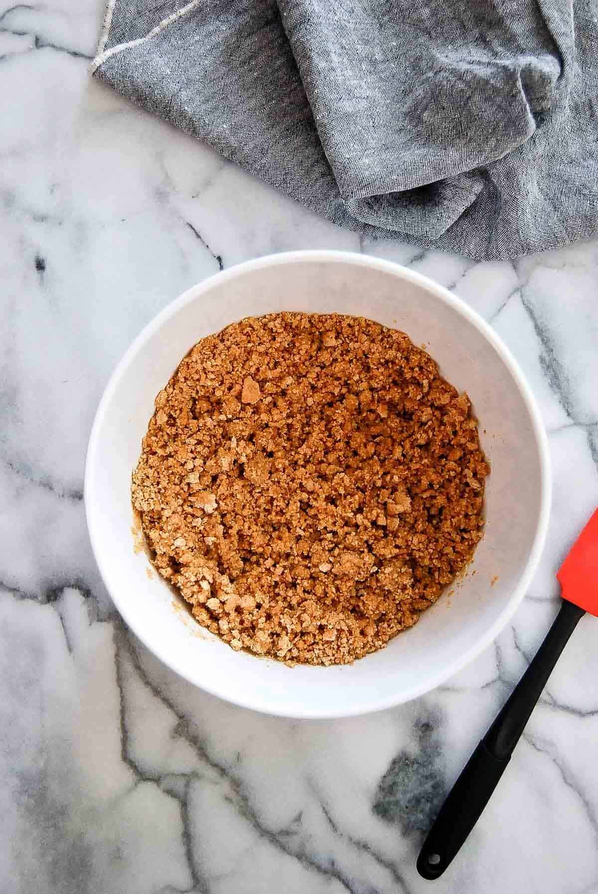 crumbled graham crackers and sugar mixed with melted butter in bowl.