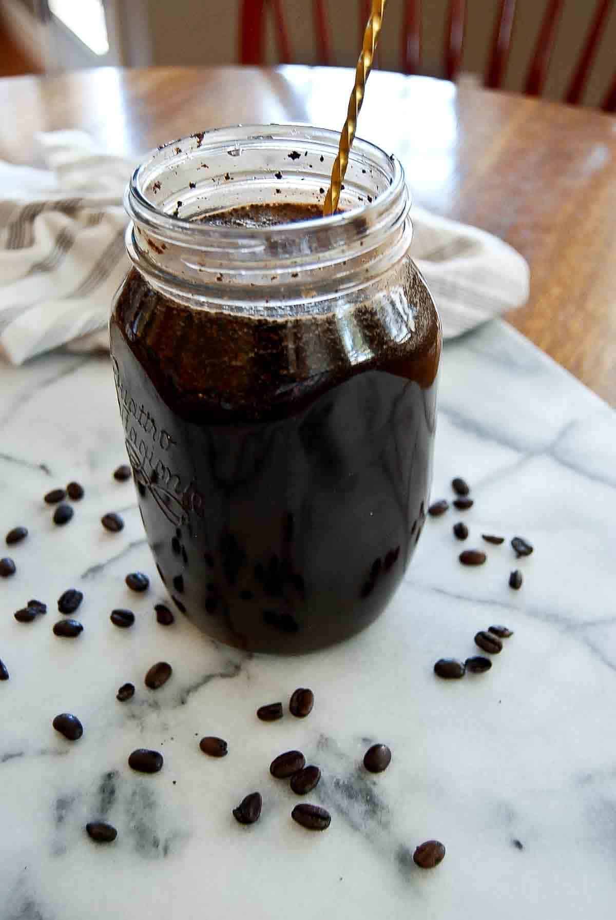 coffee ground mixed with water in mason jar, side view.