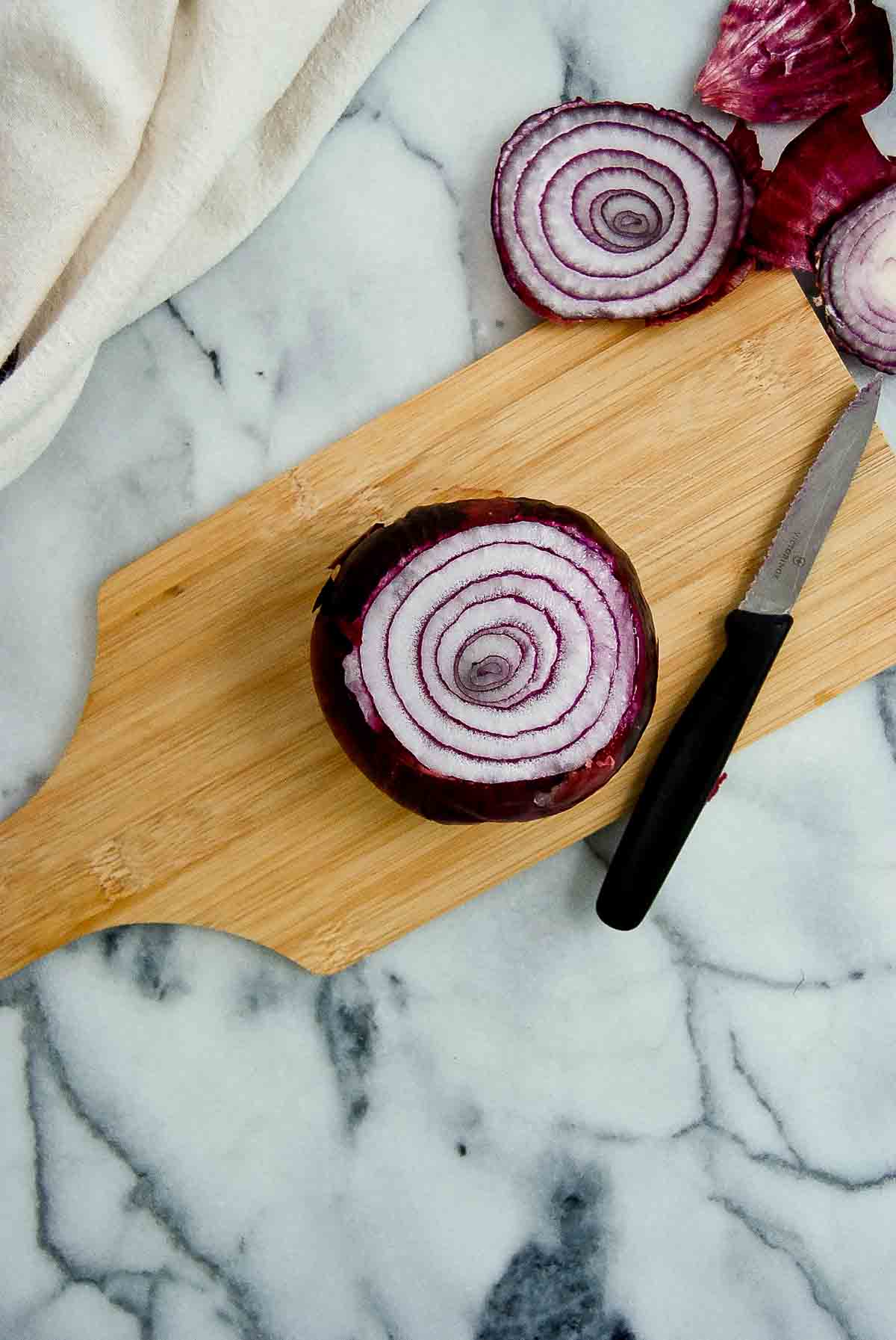 onion with ends cut off on cutting board.