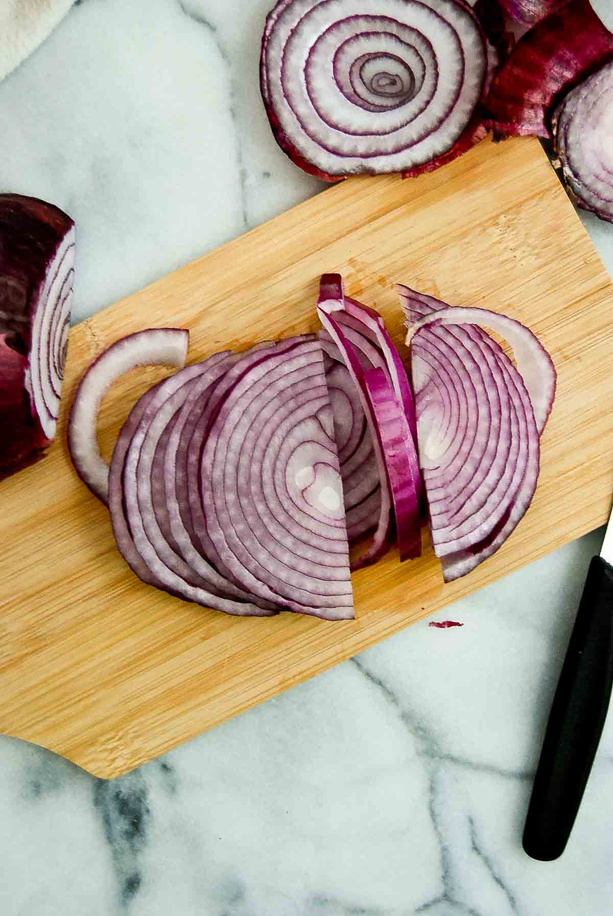 half onion radial sliced on cutting board.