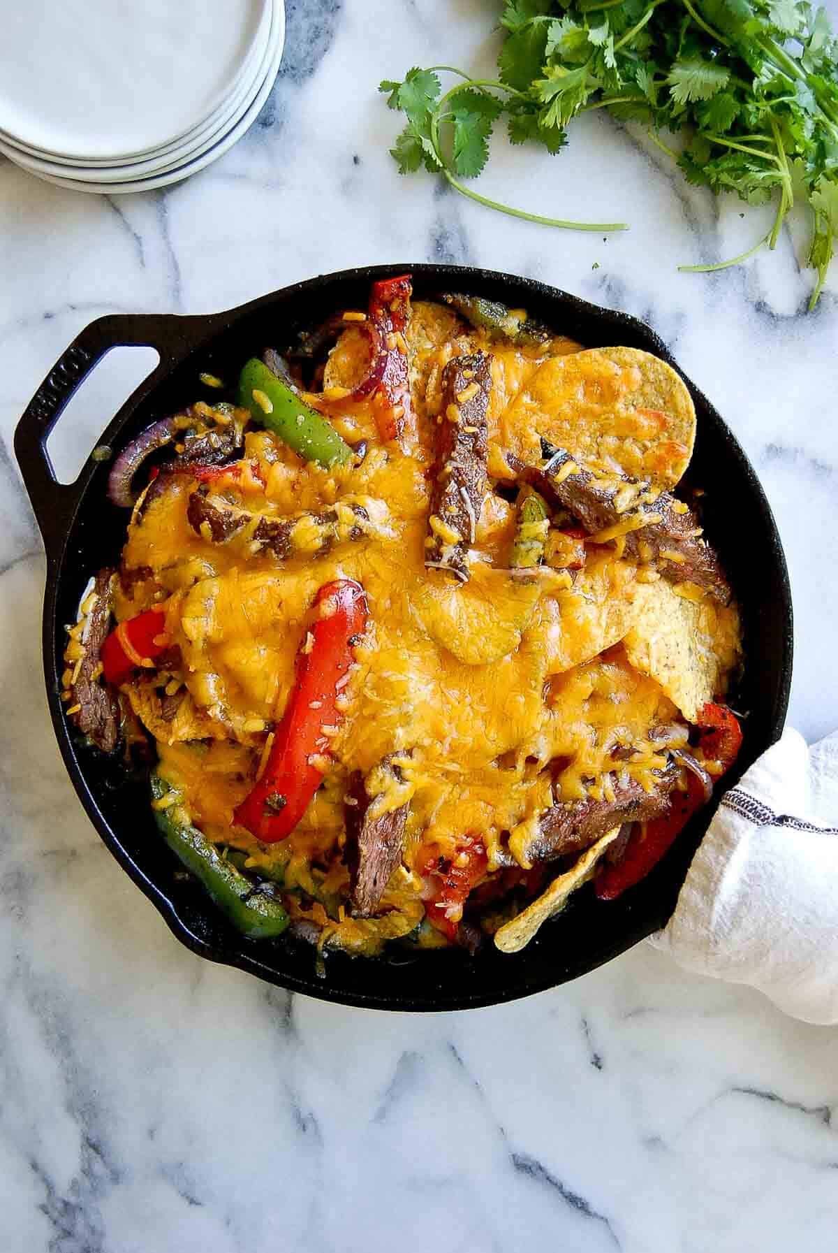 steak fajita nachos in skillet, fresh out of oven.