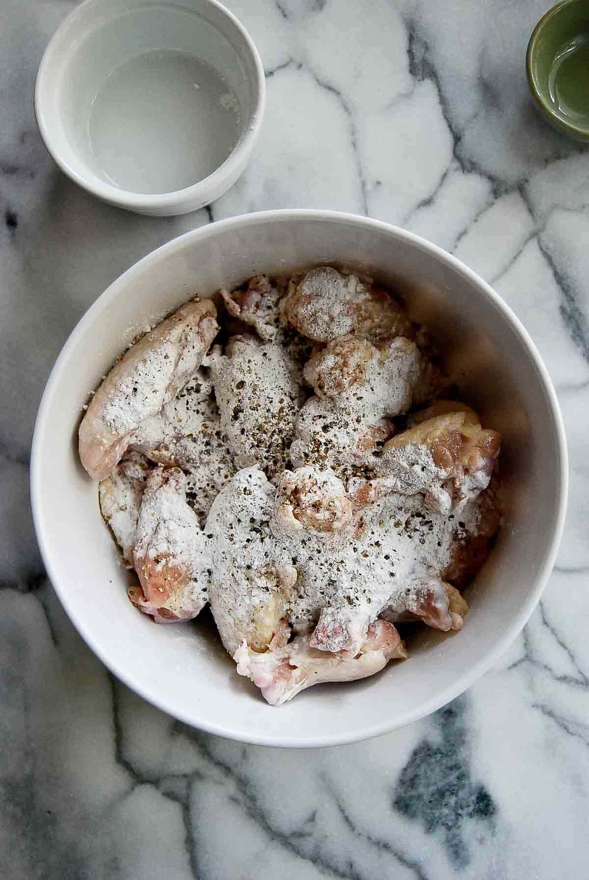 raw chicken tossed with baking powder mix in bowl.