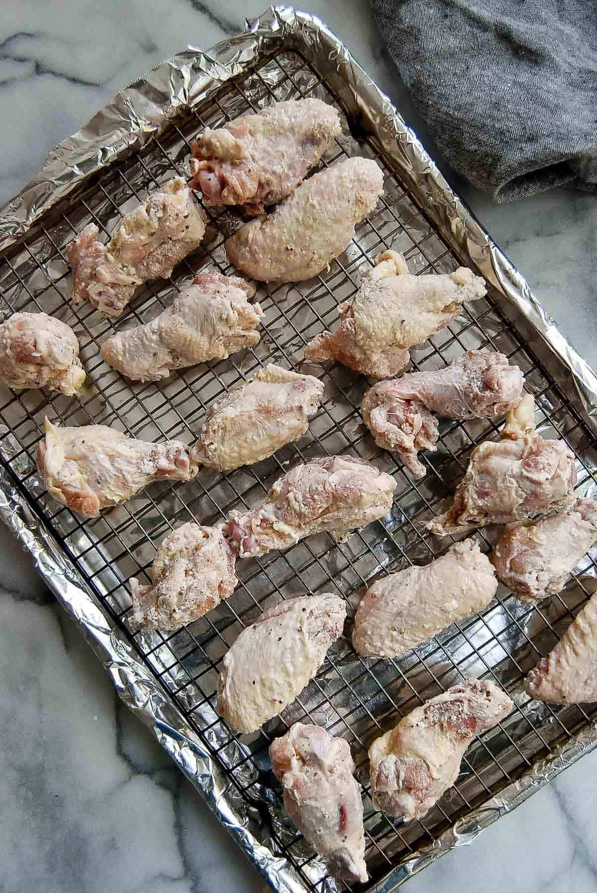 raw chicken wings placed on pan with wire rack set on top.