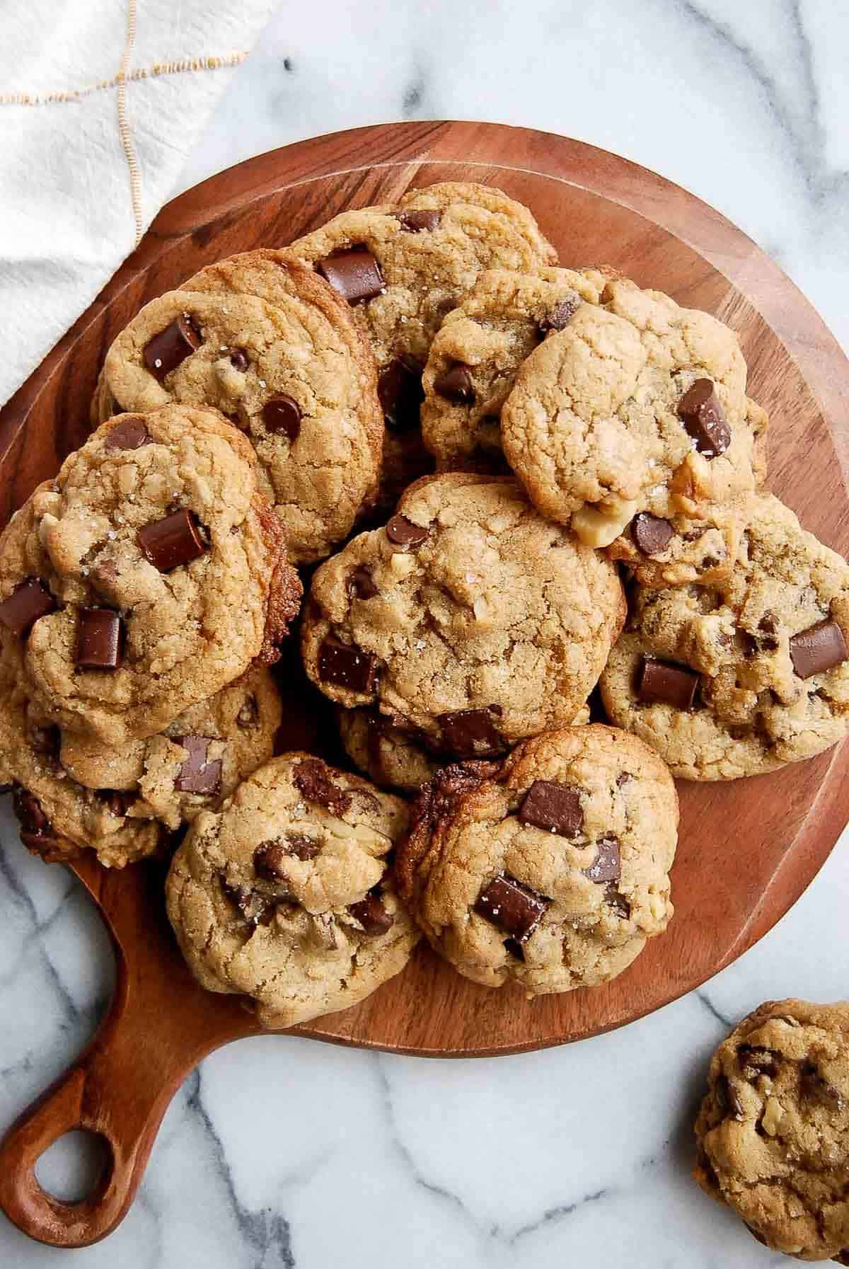 chocolate chip walnut cookies stacked on cutting board.