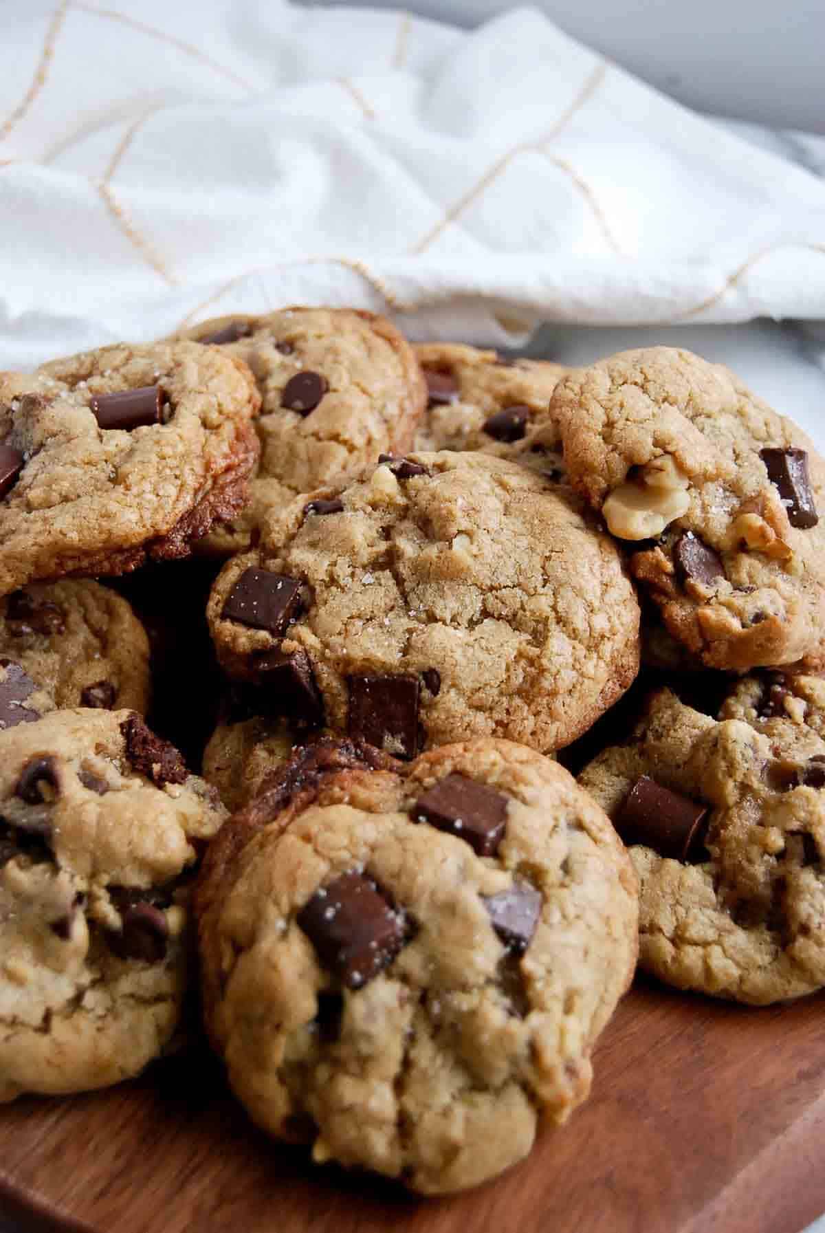 side view of chocolate chip walnut cookies on cutting board.