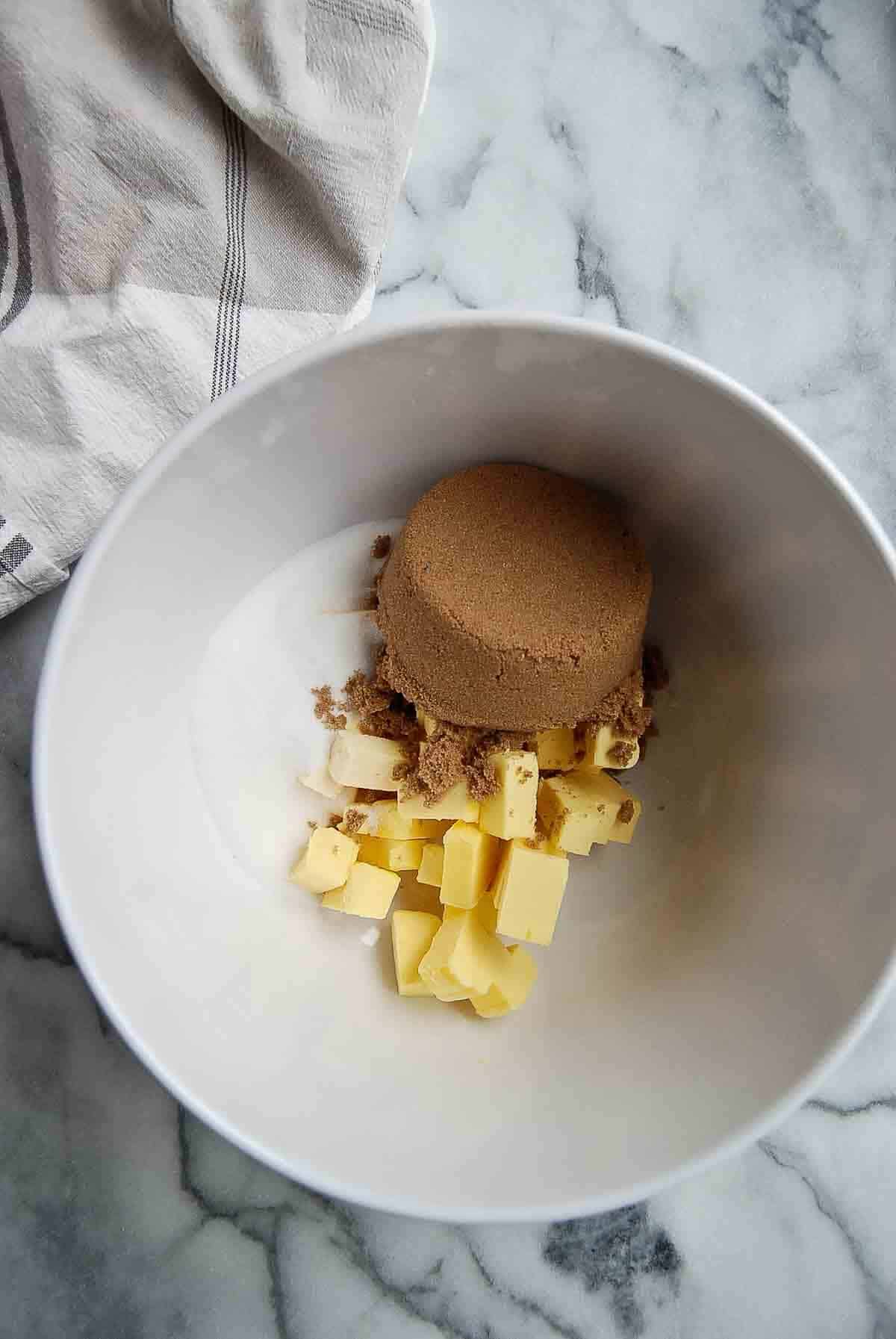 brown sugar, white sugar and cold butter cubes in bowl.