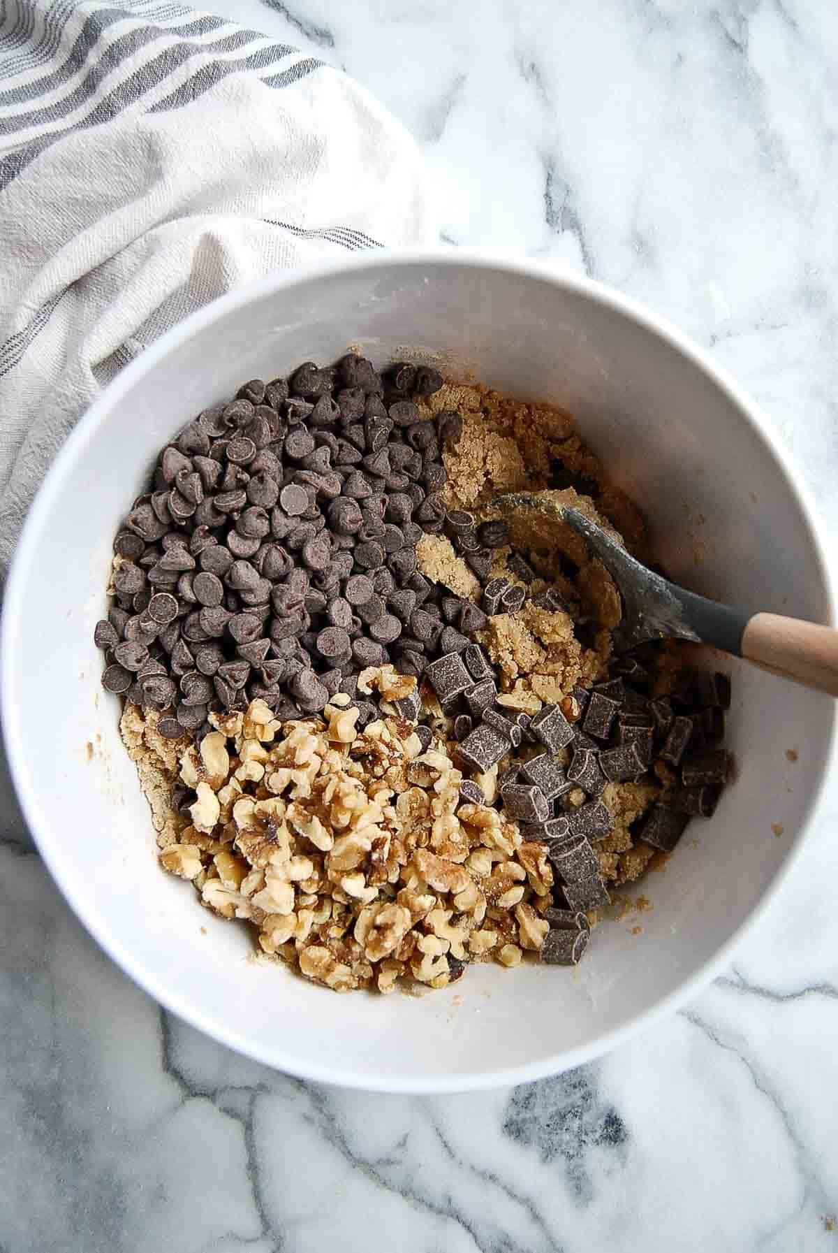 cookie dough with chocolate chips and walnuts added to bowl.