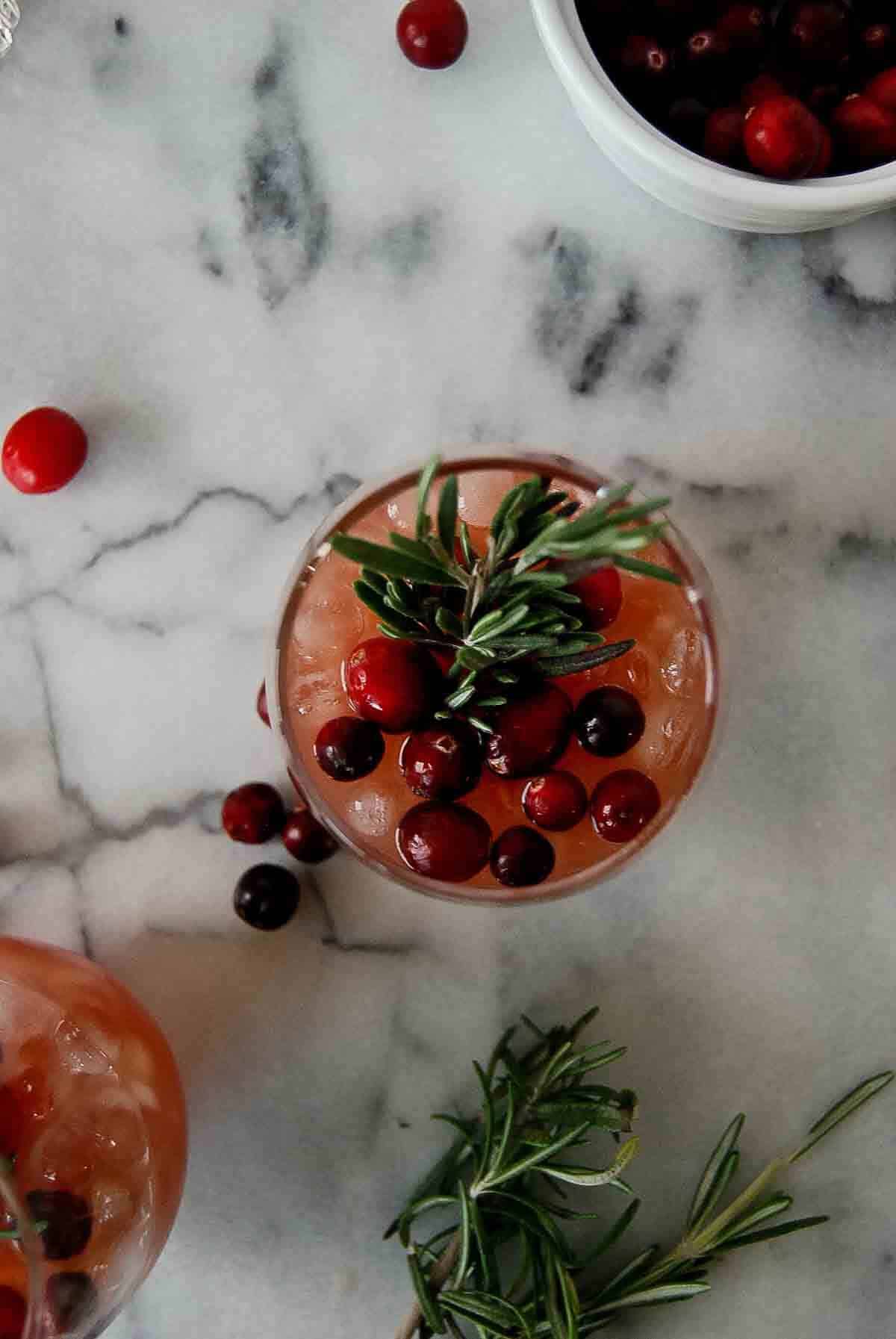 cranberry orange whiskey sour with fresh cranberries and rosemary garnish.