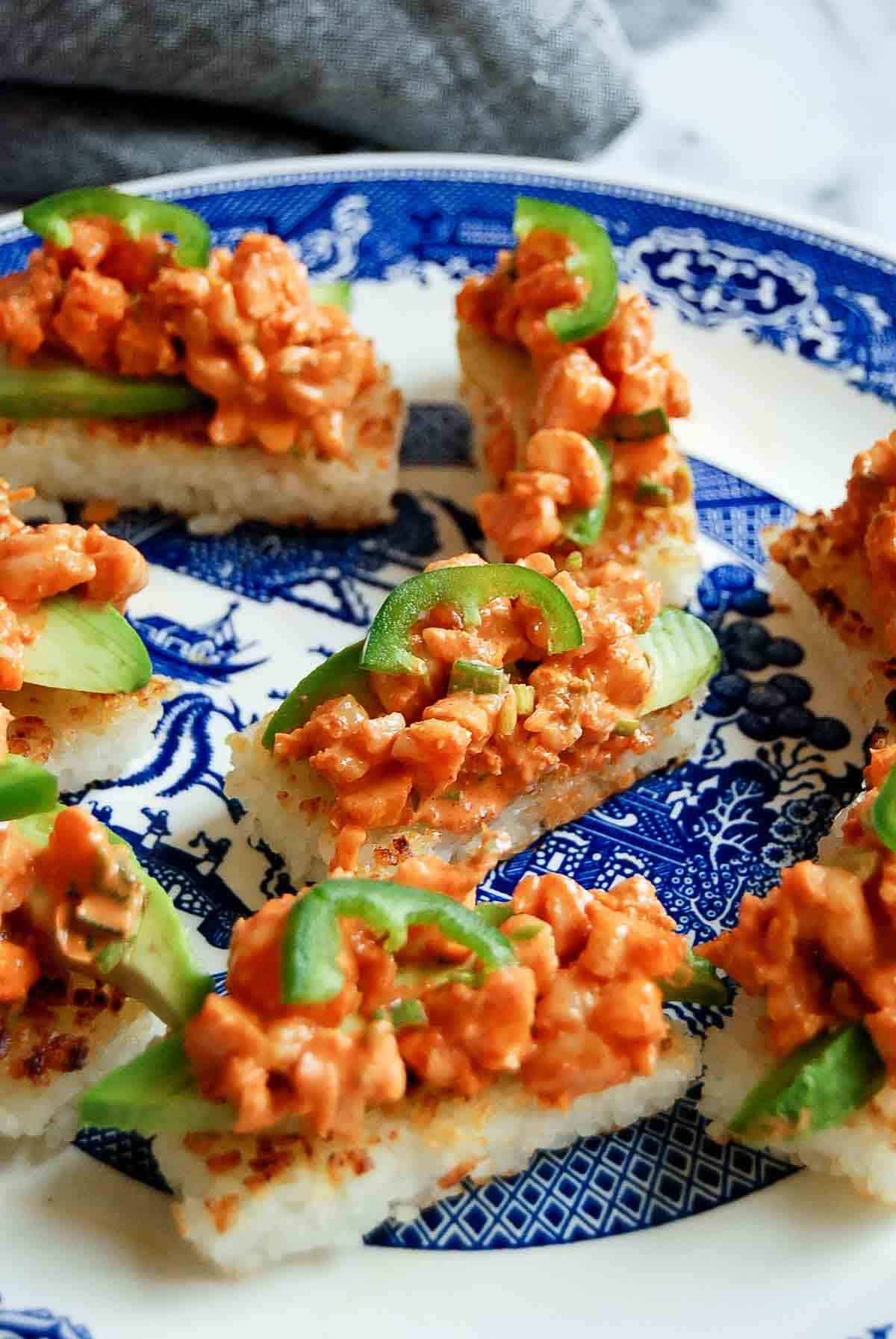 closeup of crispy rice with spicy shrimp salad with chopsticks and soy sauce on the side.