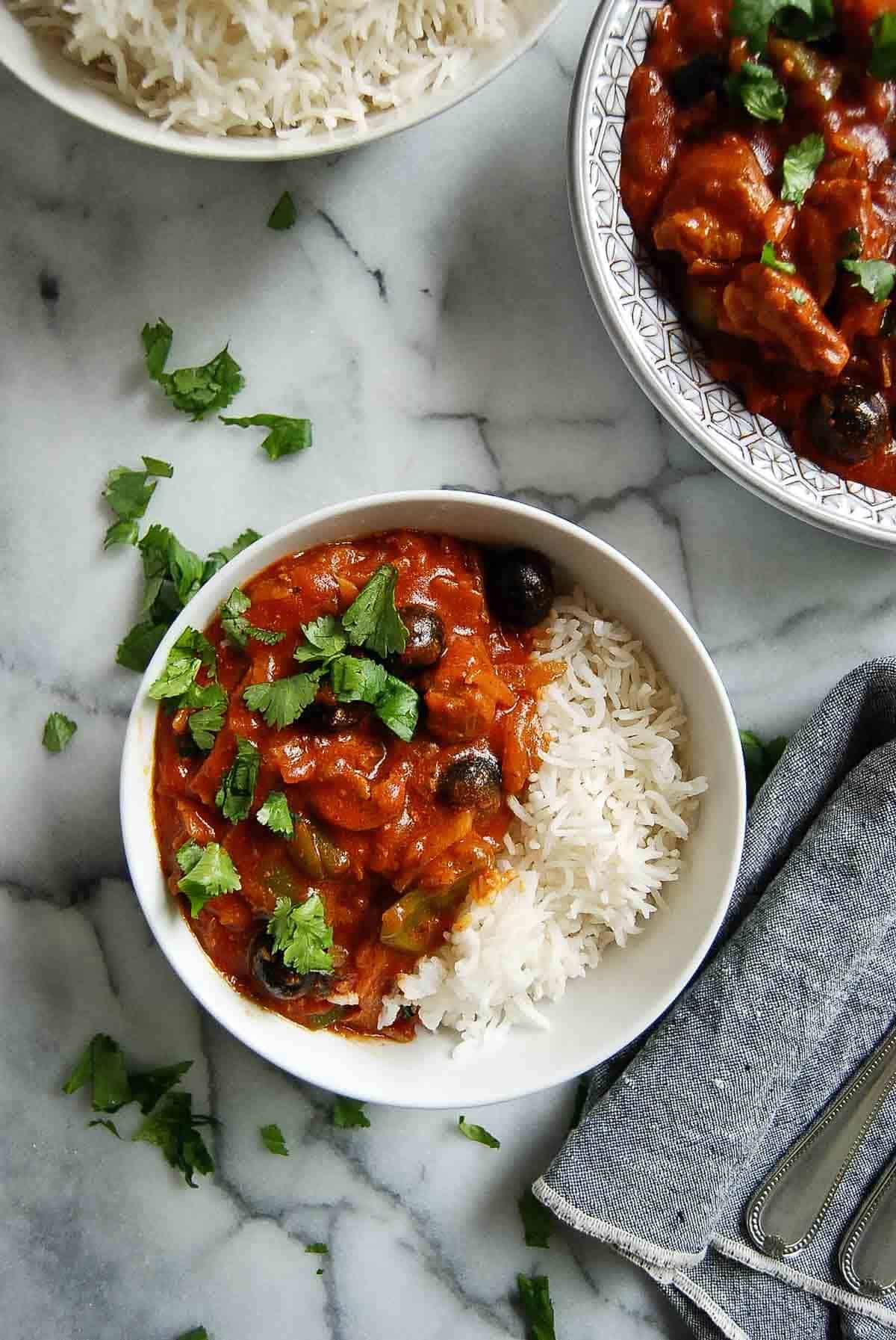 pastele stew in serving bowl, with rice to the side and 1 serving dished out on countertop.