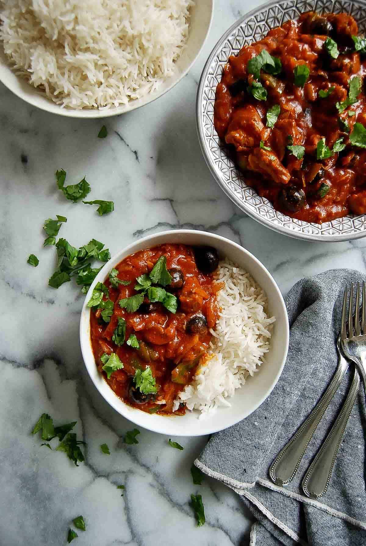 pastele stew in serving bowl, with rice to the side and 1 serving dished out on countertop.