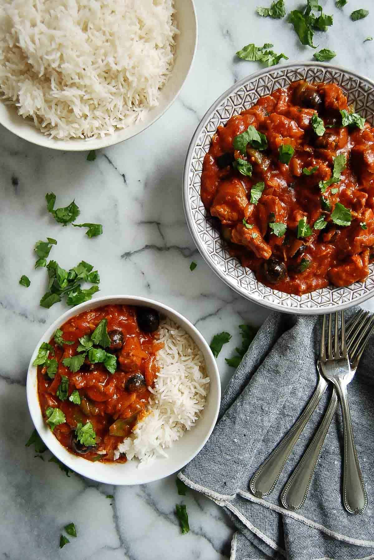 pastele stew in serving bowl, with rice to the side and 1 serving dished out on countertop.