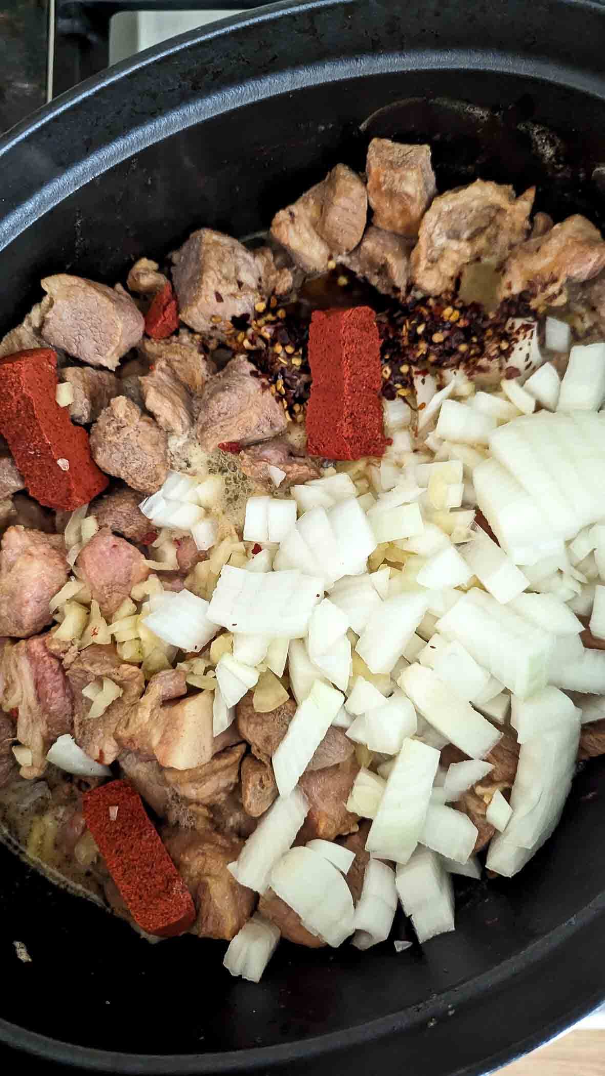 pork, onions, achiote powder, garlic and crushed red pepper in dutch oven.