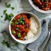 pastele stew in serving bowl, with rice to the side and 1 serving dished out on countertop.